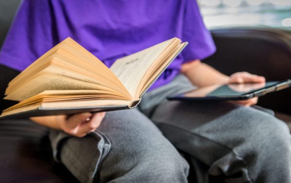 Boy holds old book and tablet