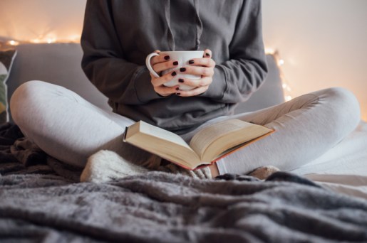 cropped-view-of-girl-reading-drinking-tea