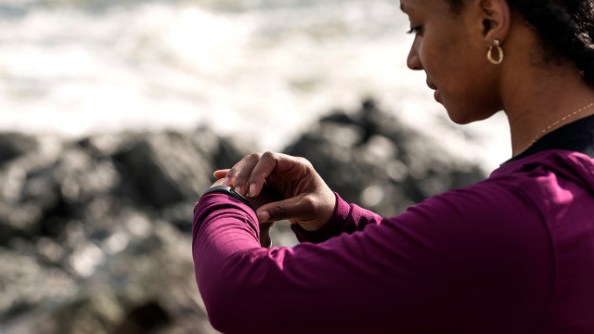 African American woman checking fitness tracker while running, Kittery, Maine, USA