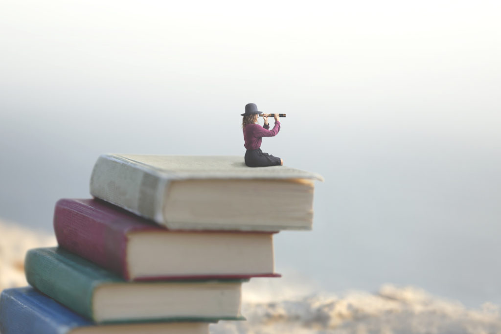 miniature woman looks at the infinity with the spyglass on a scale of books